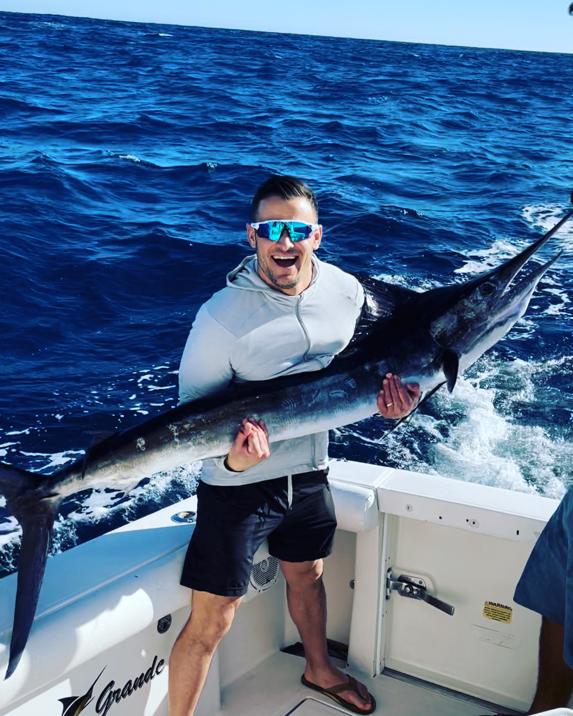Happy angler holding a large billfish on a Cabo fishing boat