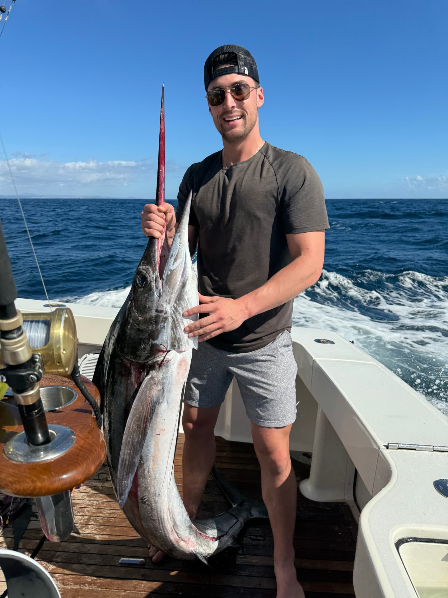 Angler holding a large striped marlin upright on a Cabo San Lucas sportfishing boat