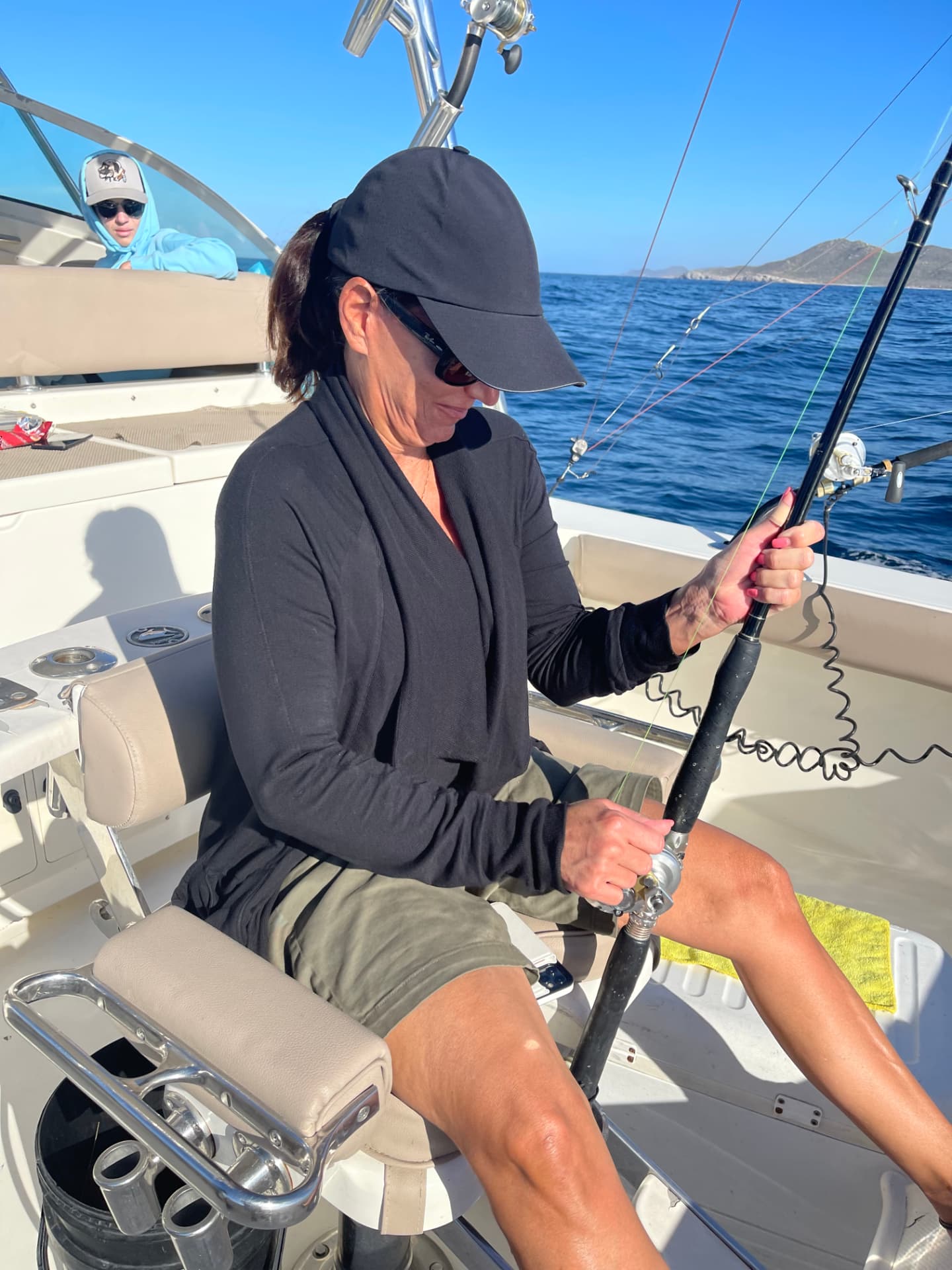 Woman working a fishing rod from the fighting chair on a Cabo boat